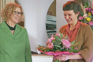 Zwei Damen, eine davon hält einen Blumenstrauß in Händen.