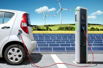 Elektro-Auto tankt Strom, im Hintergrund Photovoltaikanlage und Windrad