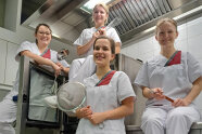 Vier Frauen mit Arbeitskleidung in einer Großküche 