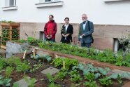 Drei Personen stehen im Garten vor dem Amtsgebäude