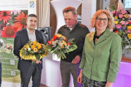 Zwei Herren mit Blumenstrauß und Dame in grünem Blazer