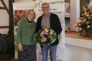 Dame und Herr mit Blumenstrauß vor einem Rollup