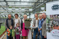 6 Erwachsene und 2 Kinder stehen in einer Gärtnerei