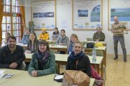 Personen sitzen an Tischen in Unterrichtsraum