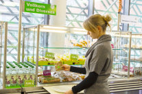 Frau wählt Vollkornbrot mit grünem Smiley an der Essensausgabe Foto: Wolfgang Pulfer / KErn