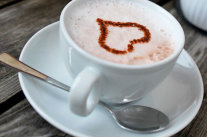 Kaffeetasse auf Tisch mit Herz im Schaum.